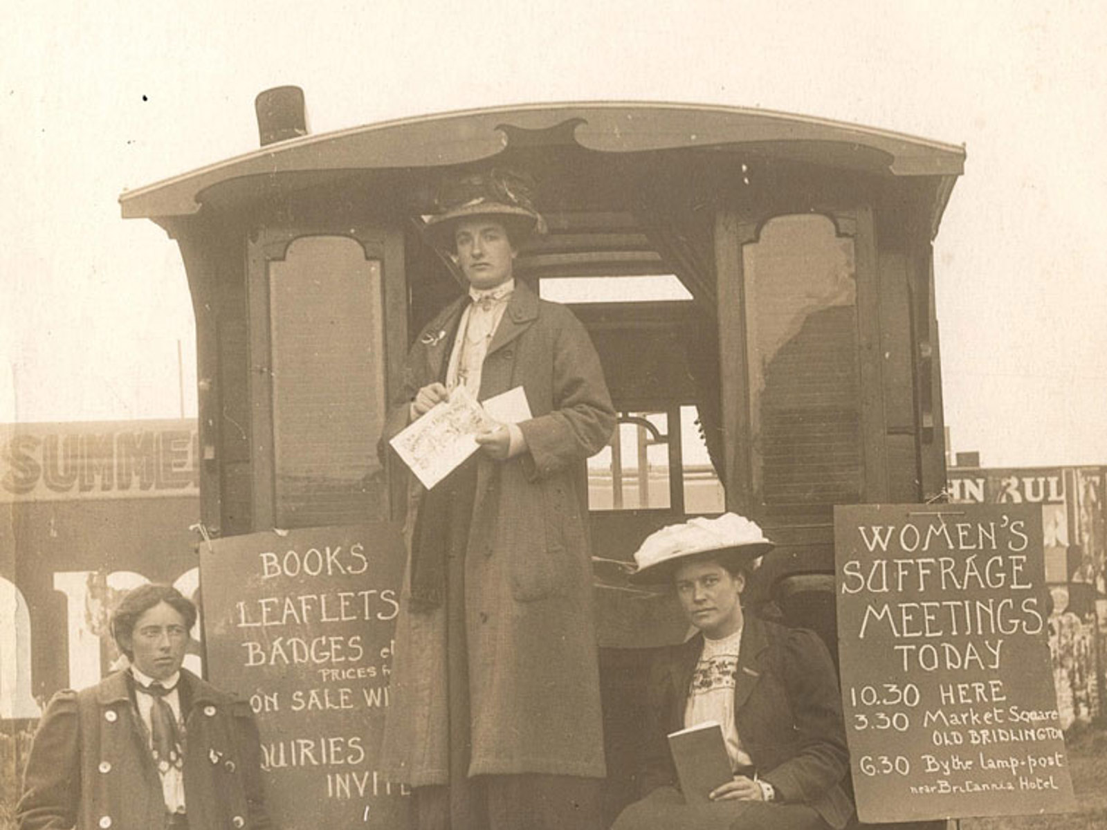 Three suffragettes standing by a caravan at Bridlington