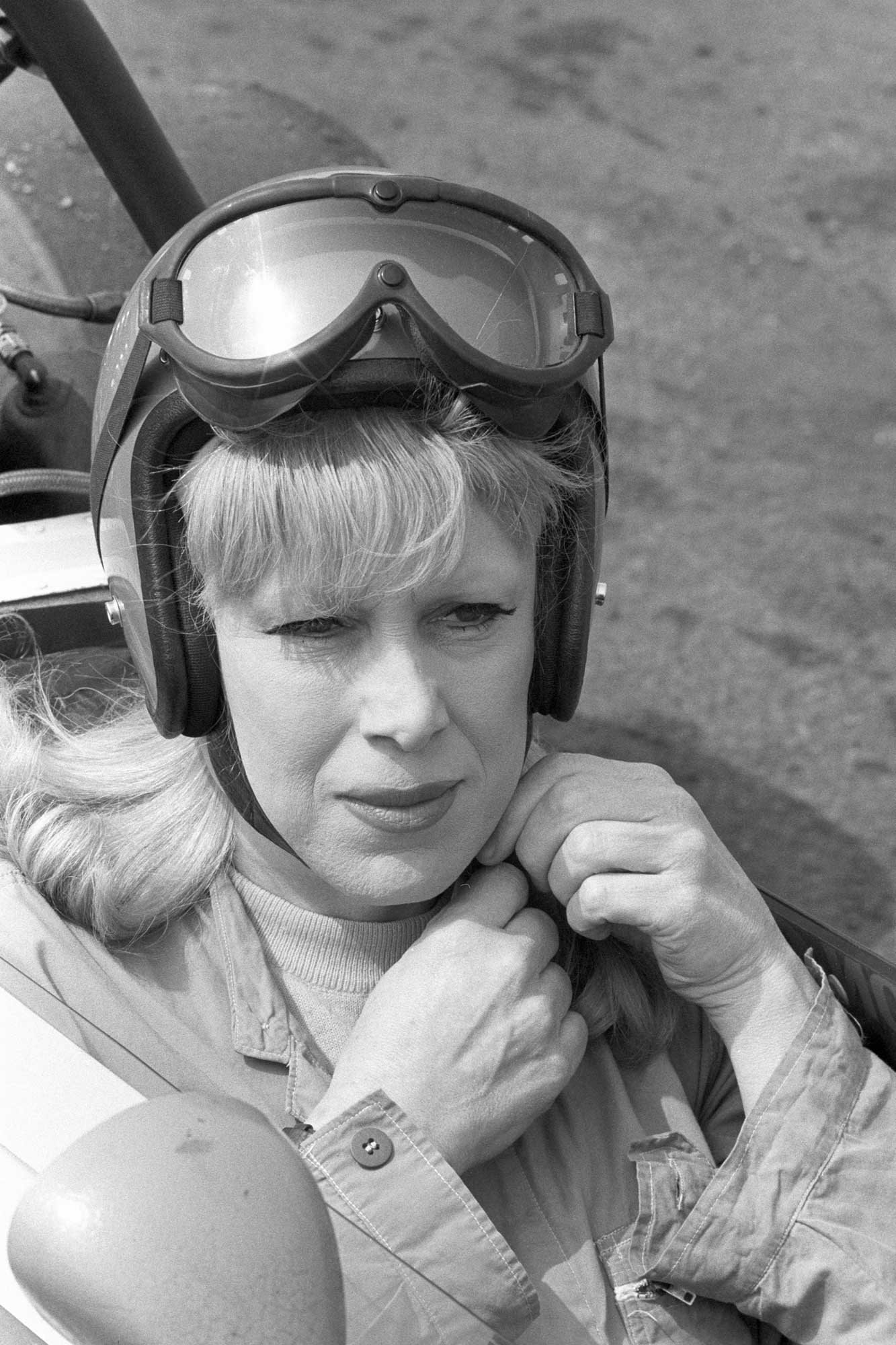 Roberta Cowell in drivers seat adjusting helmet
