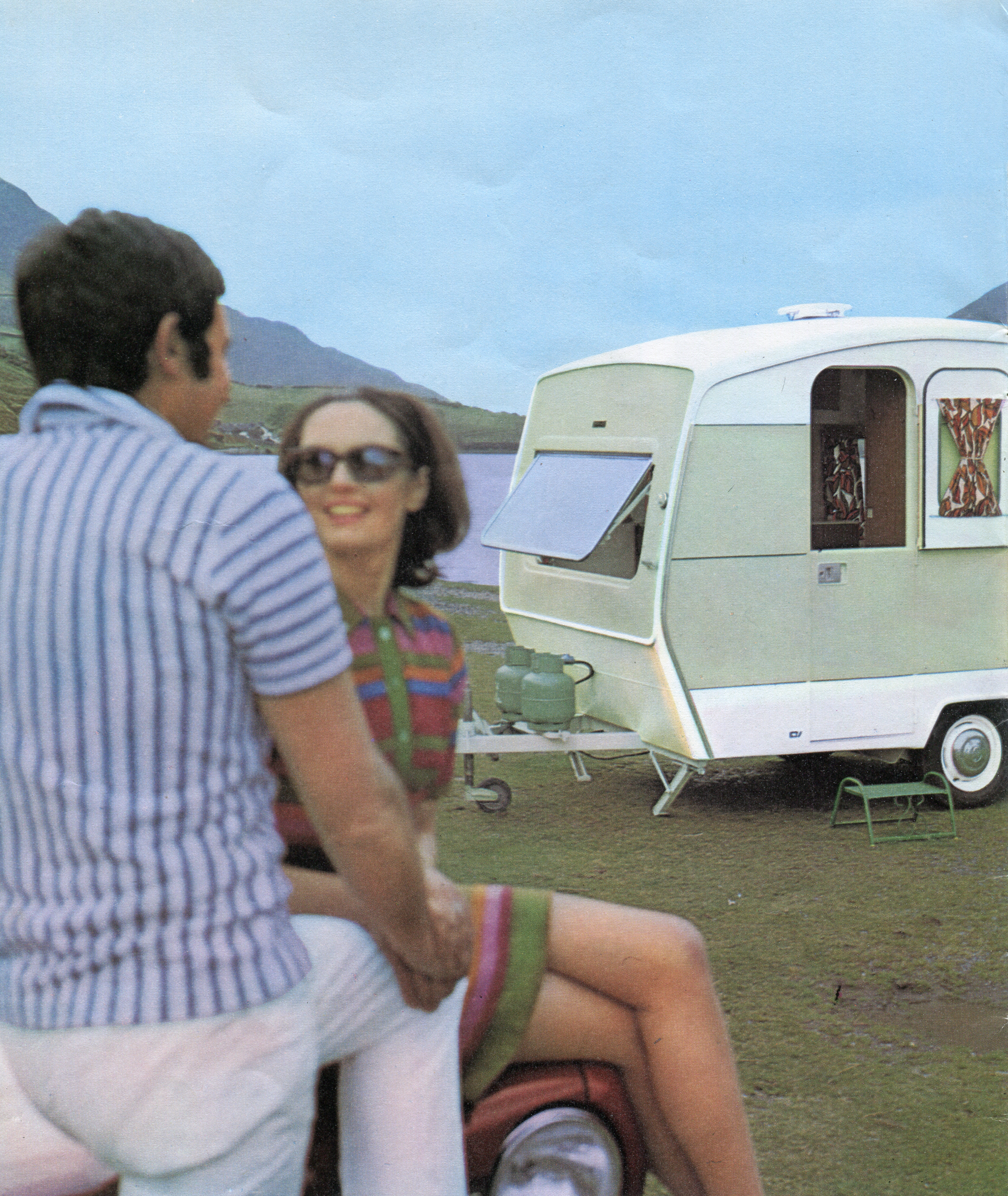 Advert shot of a couple sat by a Sprite caravan