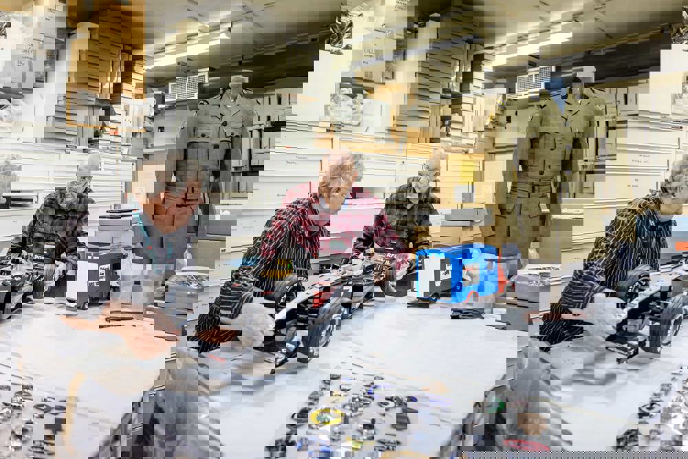 two male volunteers with formula one car model in objects store