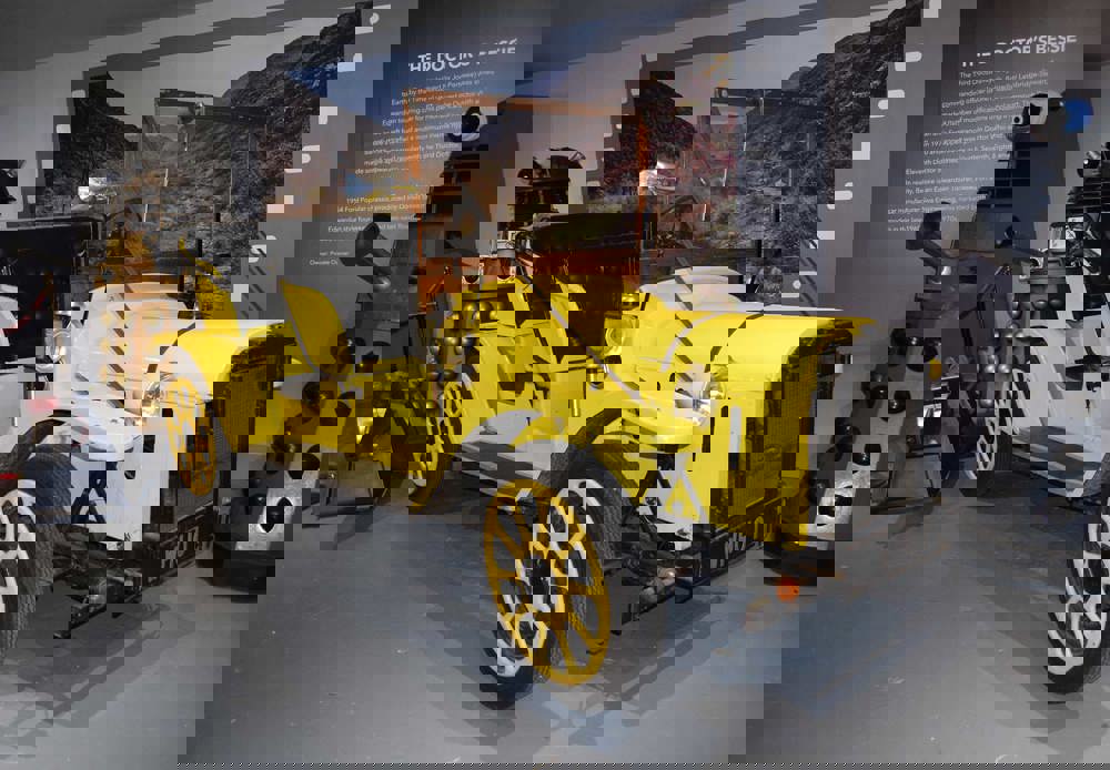 Doctor Who's Bessie on display in the 'On Screen Cars' display. The car is yellow. Two Daleks and K9 the robot dog are displayed next to the car.