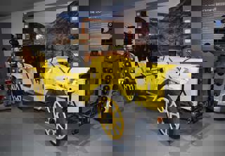 Doctor Who's Bessie on display in the 'On Screen Cars' display. The car is yellow. Two Daleks and K9 the robot dog are displayed next to the car.