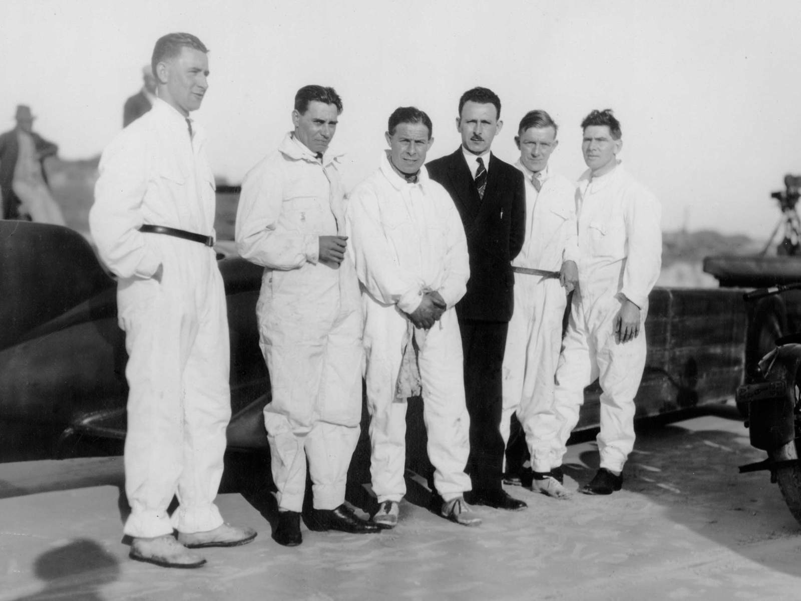 Five mechanics standing in front of Golden Arrow at Daytona Beach, 1929