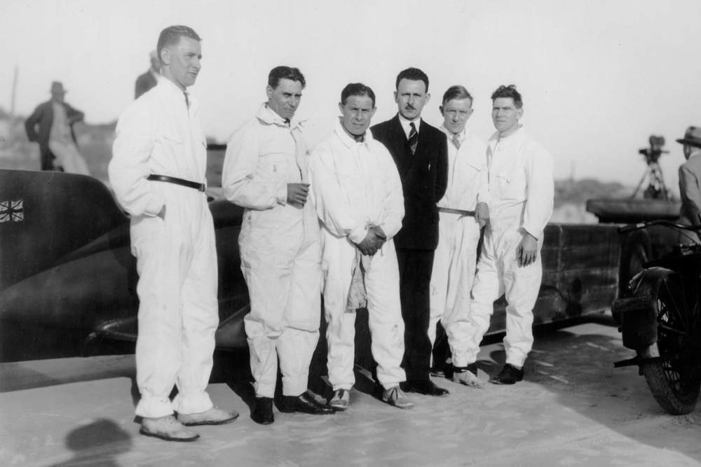 Five mechanics standing in front of Golden Arrow at Daytona Beach, 1929