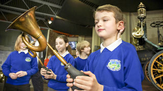 school boy with car horn in the museum