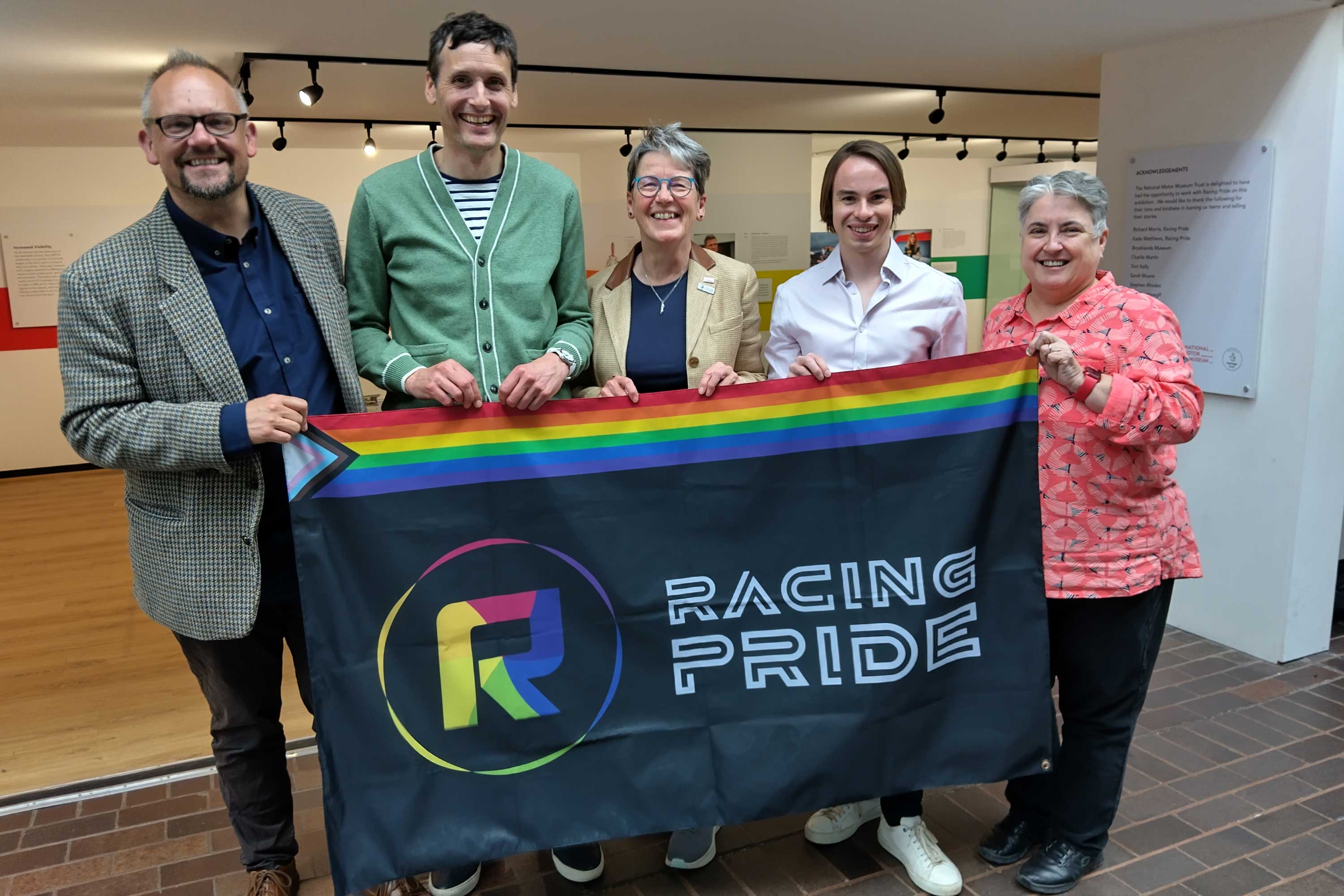 Richard Morris with National Motor Museum staff holding flag outside exhibition