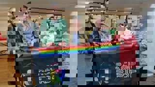 Richard Morris with National Motor Museum staff holding flag outside exhibition