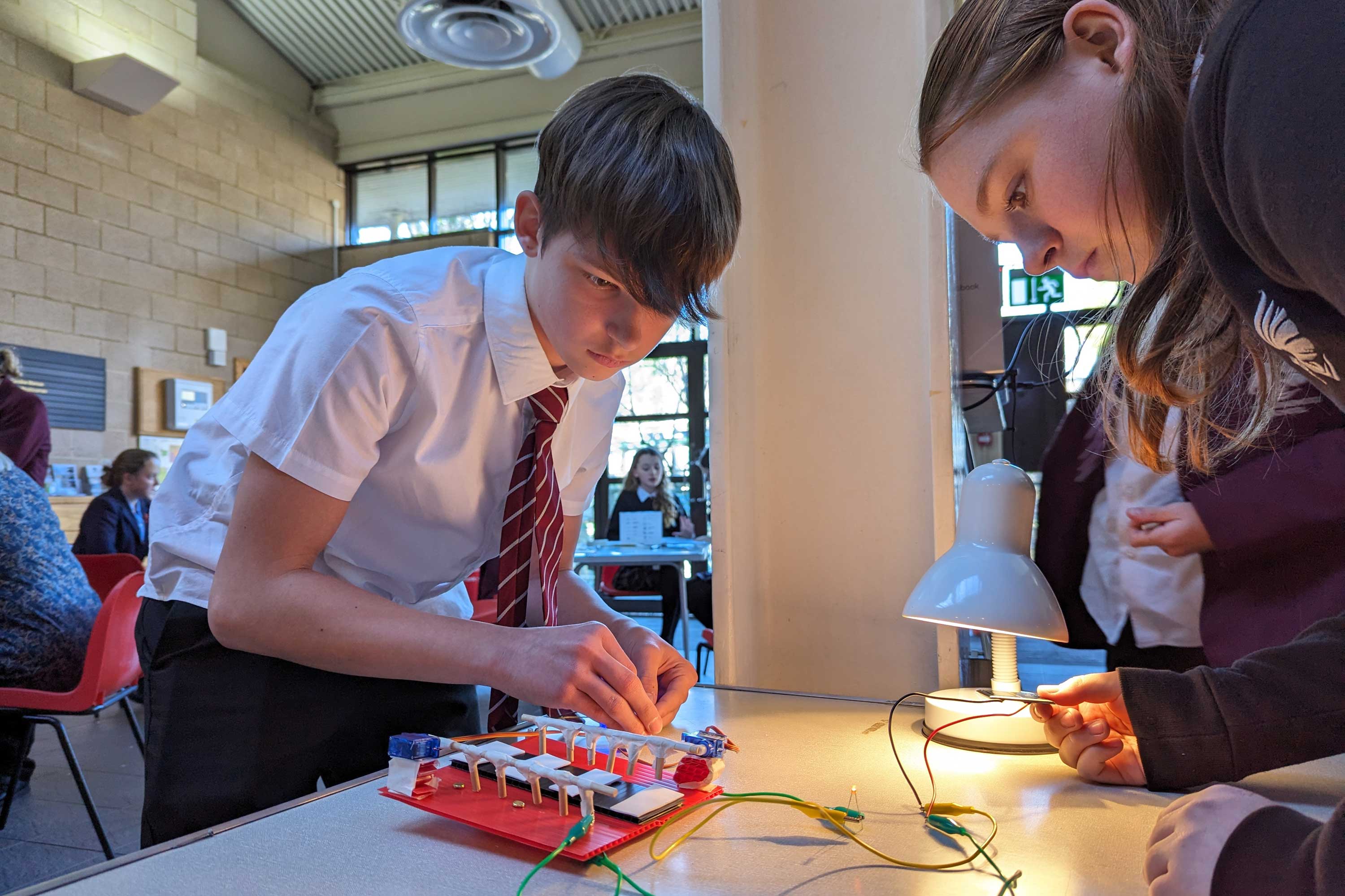 school boy and girl standing up over a table conducting an engineering experiment