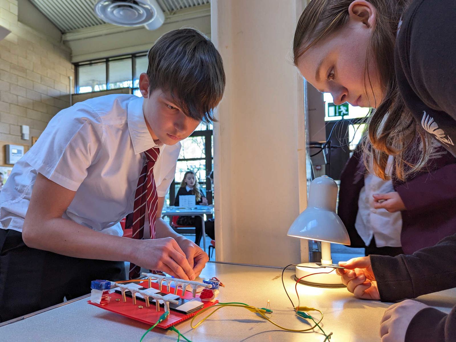 school boy and girl standing up over a table conducting an engineering experiment