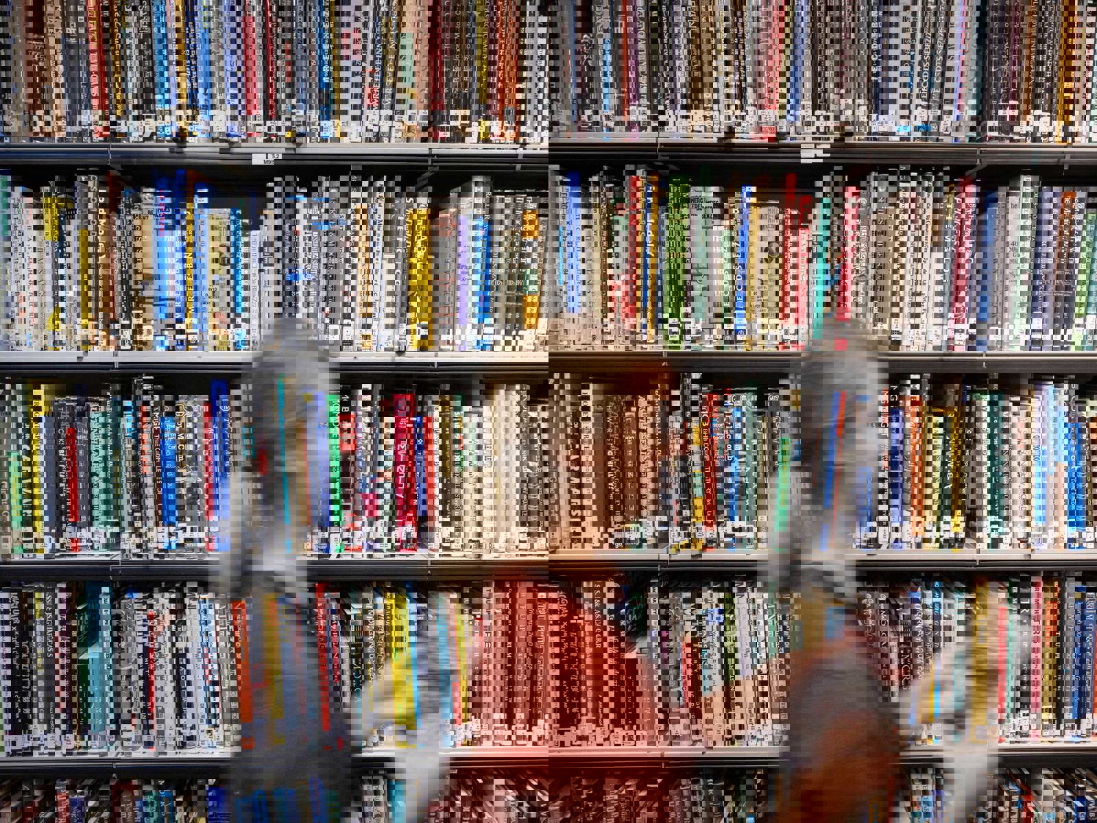 shelving with books as staff member walks by