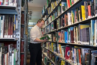Shelves of books in the reference library with male curator