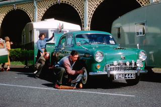 Edgar Thorne’s co-driver and wife polish his outfit for the Concours d’Elegance on Madeira Drive, Brighton, 1959.