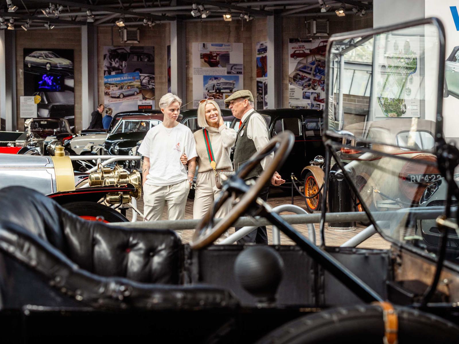 Two female visitors speak to a member of staff in the National Motor Museum