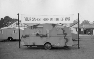 Camouflaged caravan under the banner "Your safest home in war"