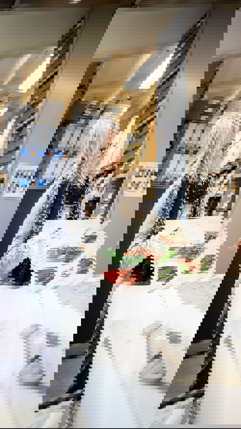 female curator holding up archive material for colleague to view in the archive store