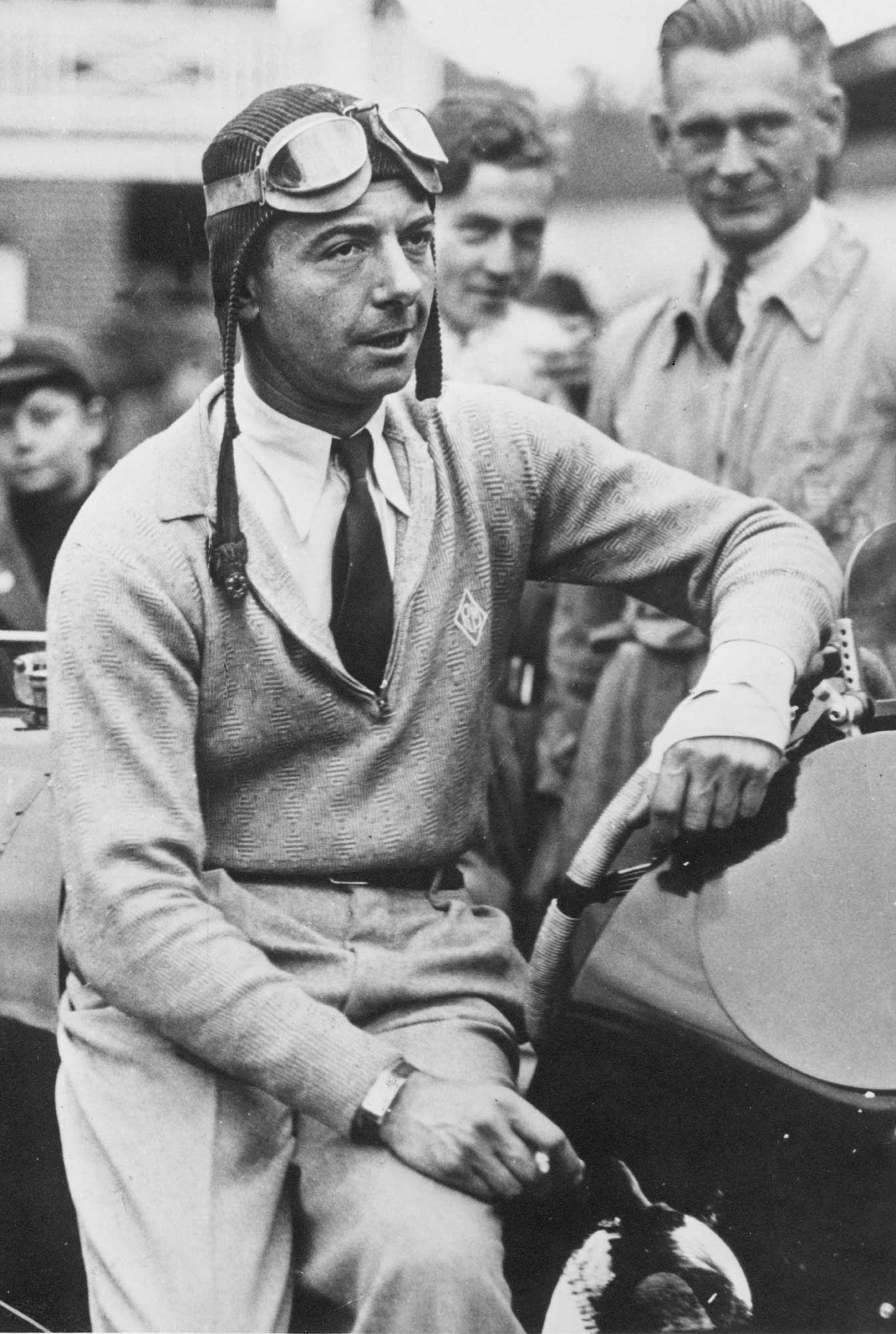 Raymond Mays leaning against racing car smoking