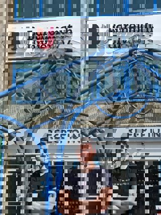 Bournemouth University student standing in front of the uni entrance