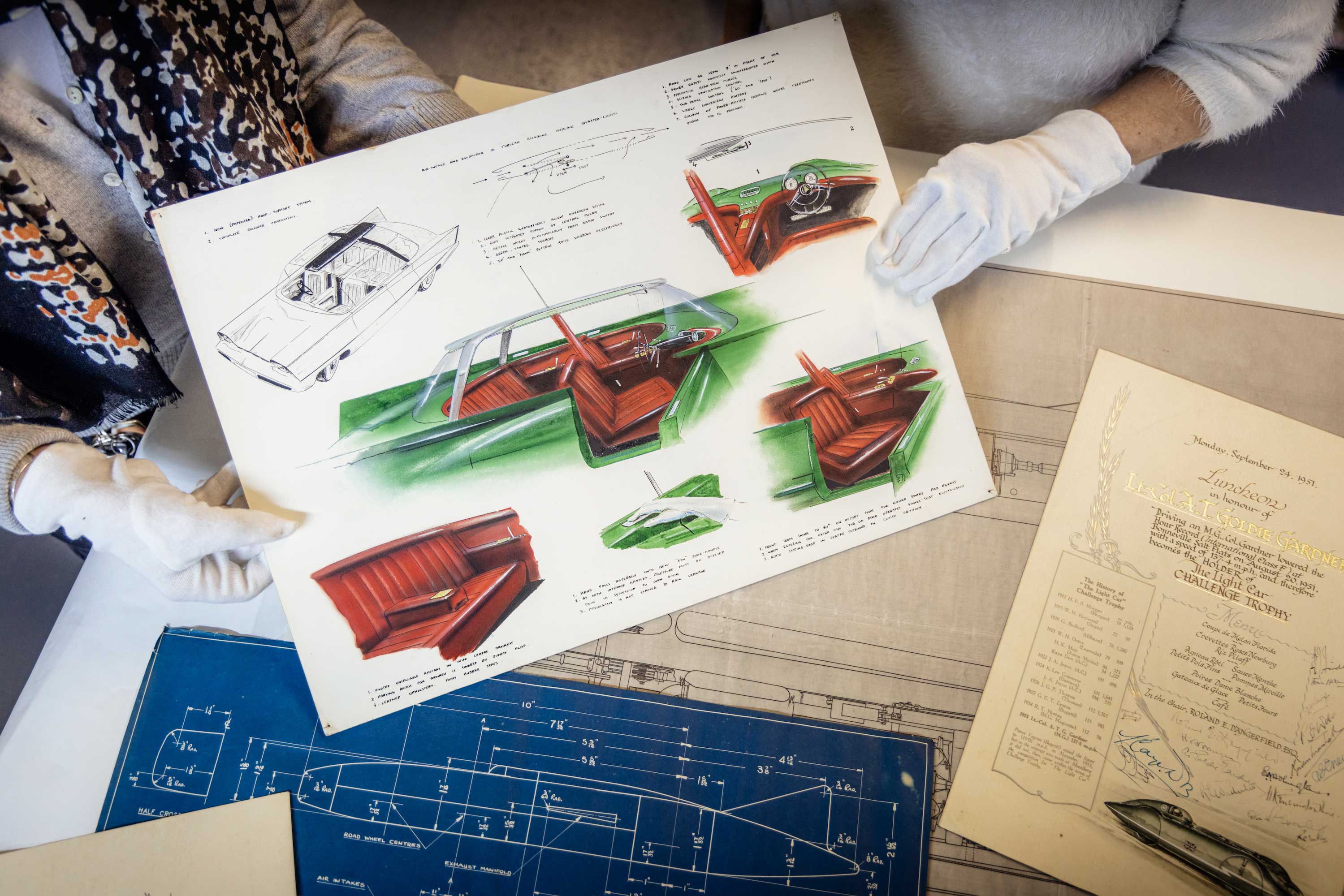 concept car drawings in colour held up by members of staff