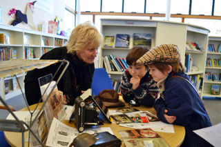 lady conducting outreach session with two boys at a library using objects from the museum's collections