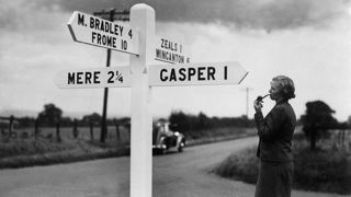 Archive image of lady at a crossroads looking at road sign c1930s