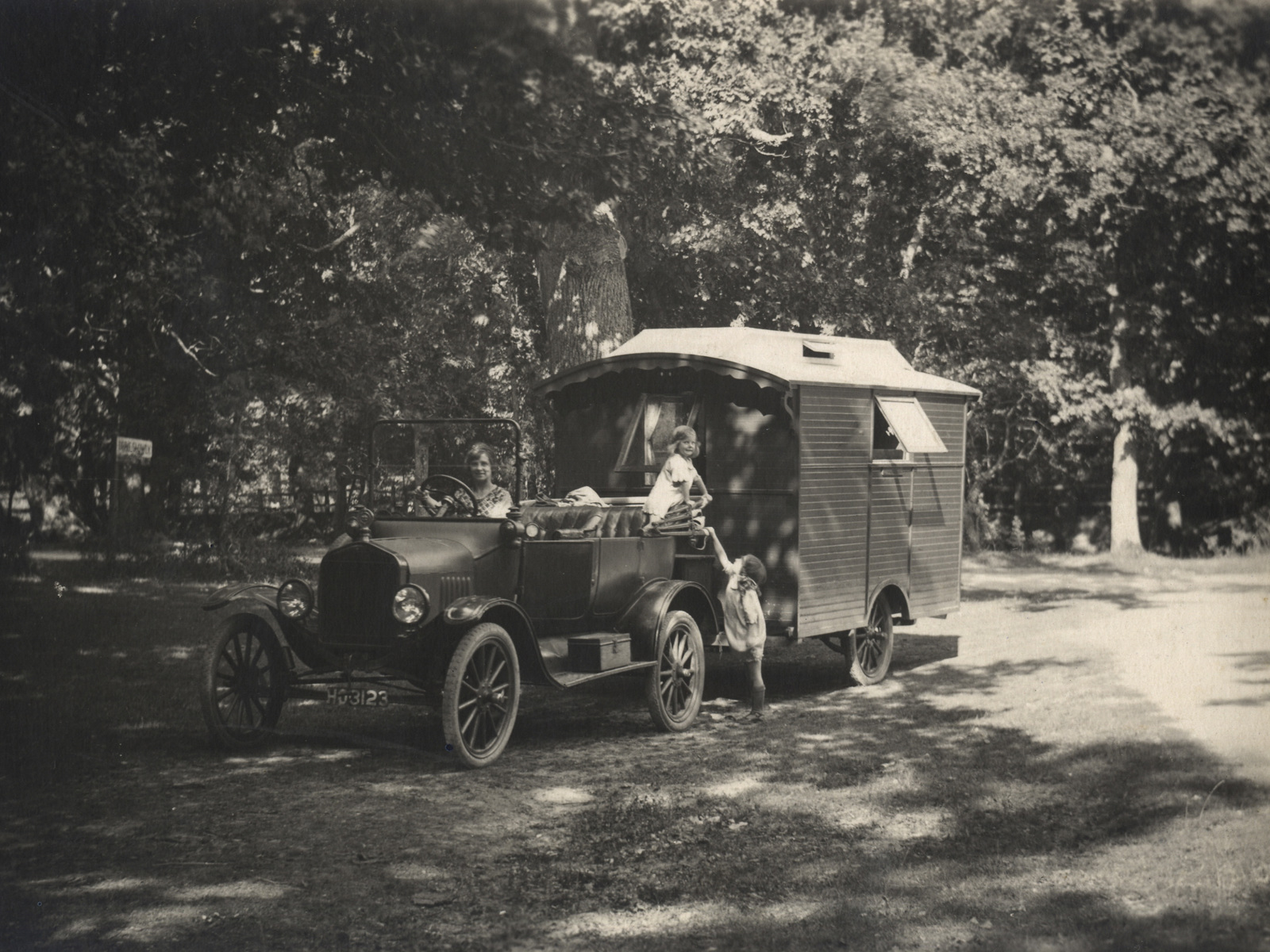 Woman driving a 1921 Ford Model T towing a caravan with two children