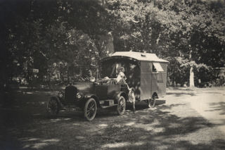 Woman driving a 1921 Ford Model T towing a caravan with two children