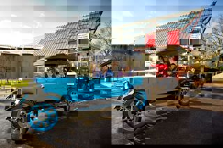 group of school children in the Austin Twelve Clifton with museum and replica red routemaster bus in background