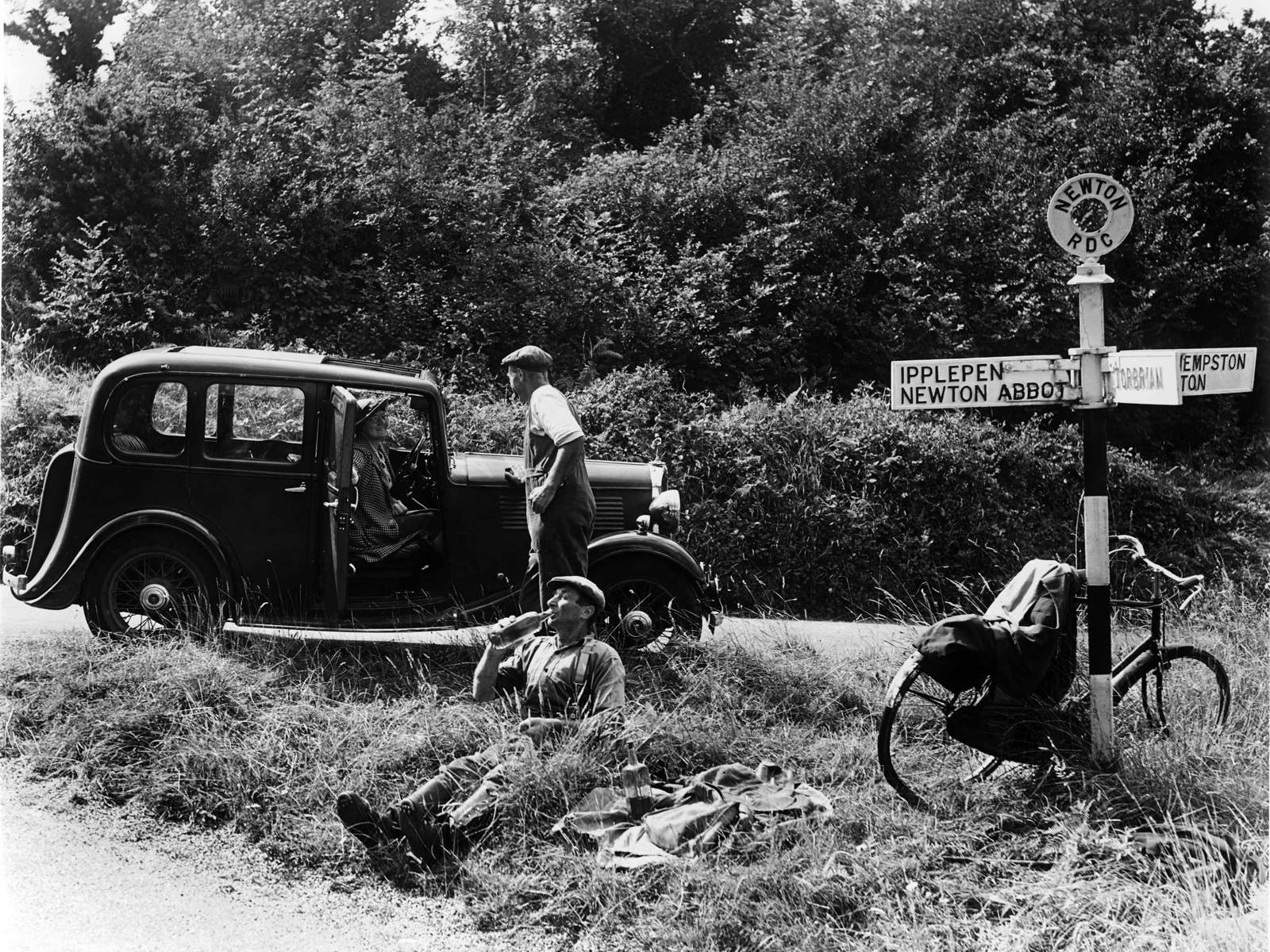 Archive image of two men at a crossroads with car