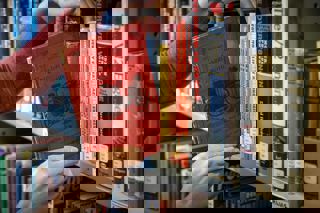 pair of hands placing a book on a shelf